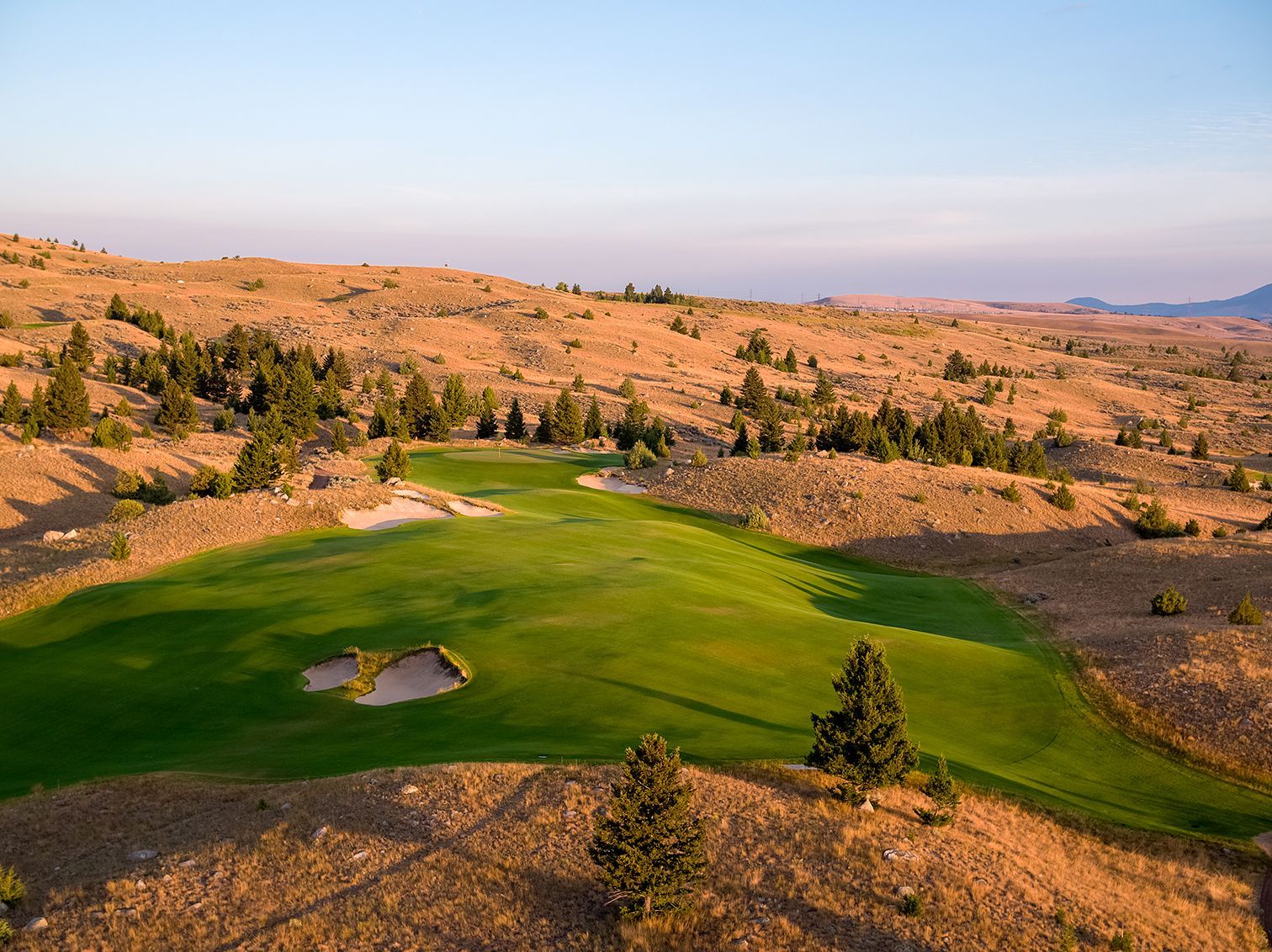 An aerial view of a golf course in the middle of a desert.