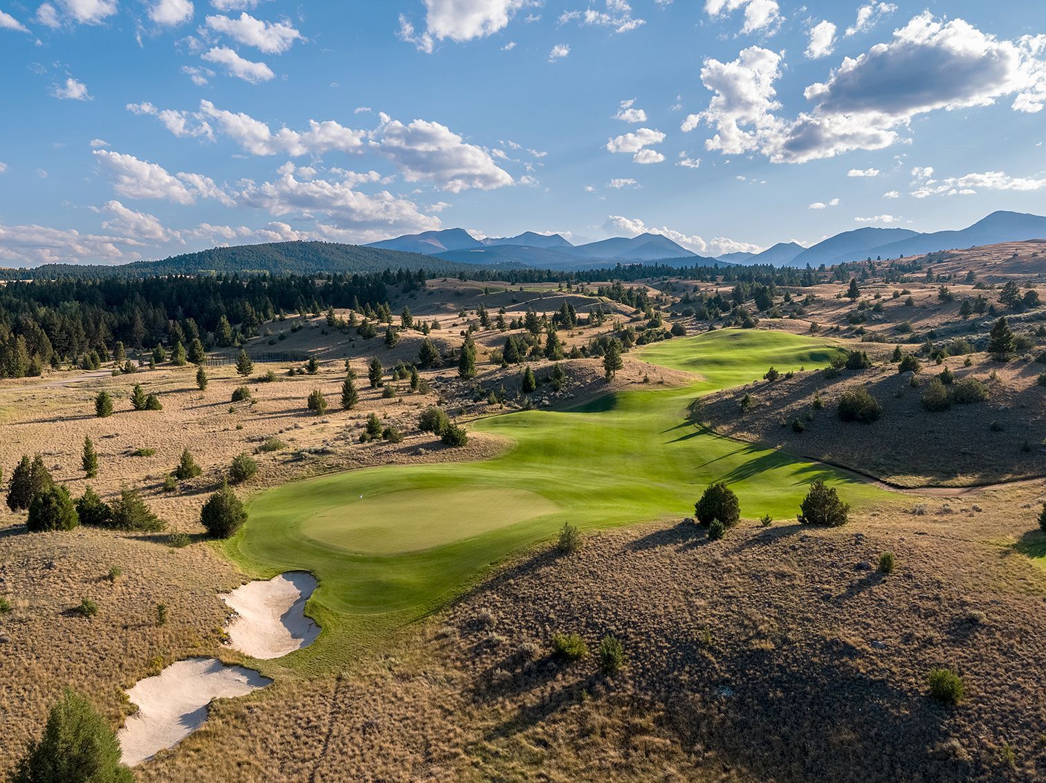 An aerial view of a golf course in the desert with mountains in the background.