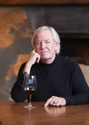 A man is sitting at a table with a glass of wine.