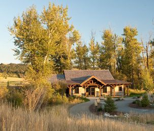 A log cabin is sitting in the middle of a field surrounded by trees.