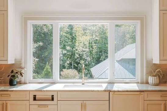 Green siding and black-framed windows on a house with brown trim and gutters.