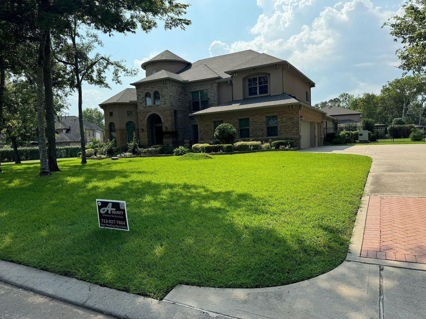 Large, stone house with well-manicured lawn and a sign in front.