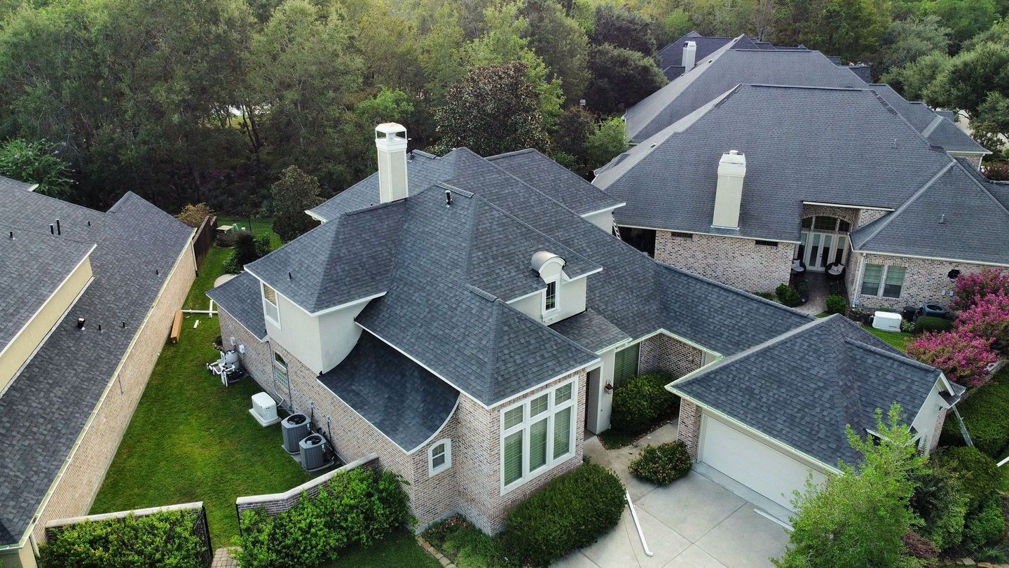 Aerial view of houses with dark gray roofs and green lawns.
