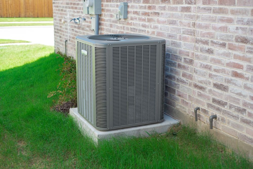 Outdoor HVAC unit beside a brick house, sitting on a concrete pad in a grassy yard — Sparky Mid North Coast In Forster, NSW