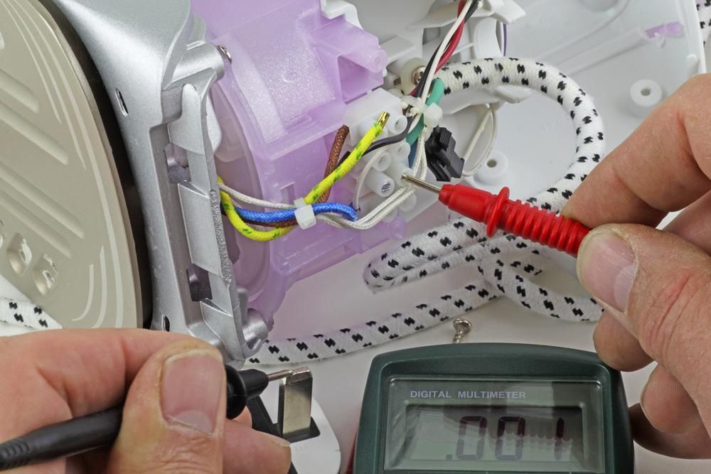 A Person is Using a Multimeter to Test an Iron — Sparky Mid North Coast In Forster, NSW