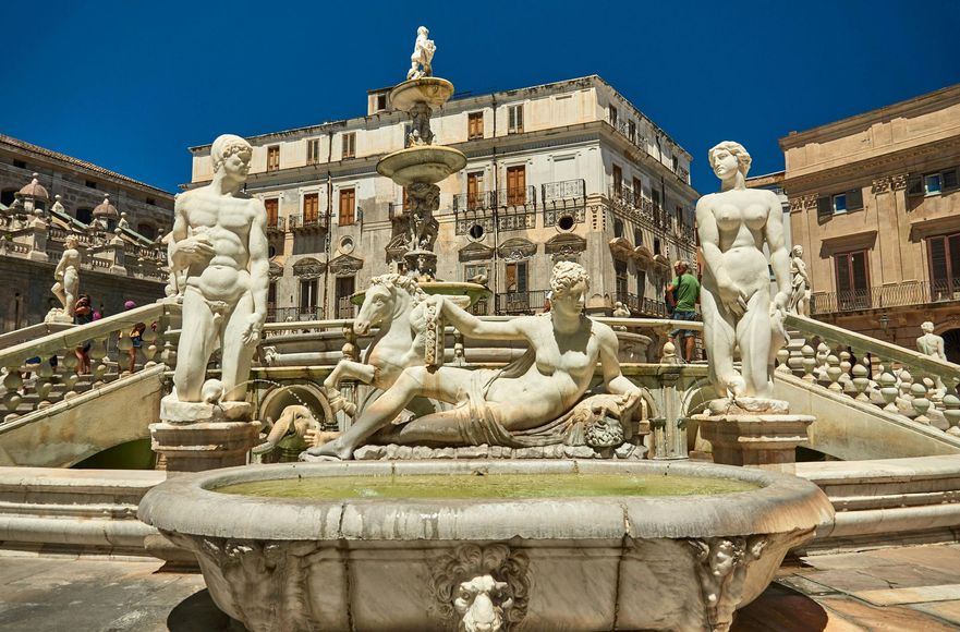 La fontana di Piazza Pretoria a Palermo, in Italia, è caratterizzata da elaborate statue in marmo raffiguranti figure e animali, sullo sfondo di un edificio storico.