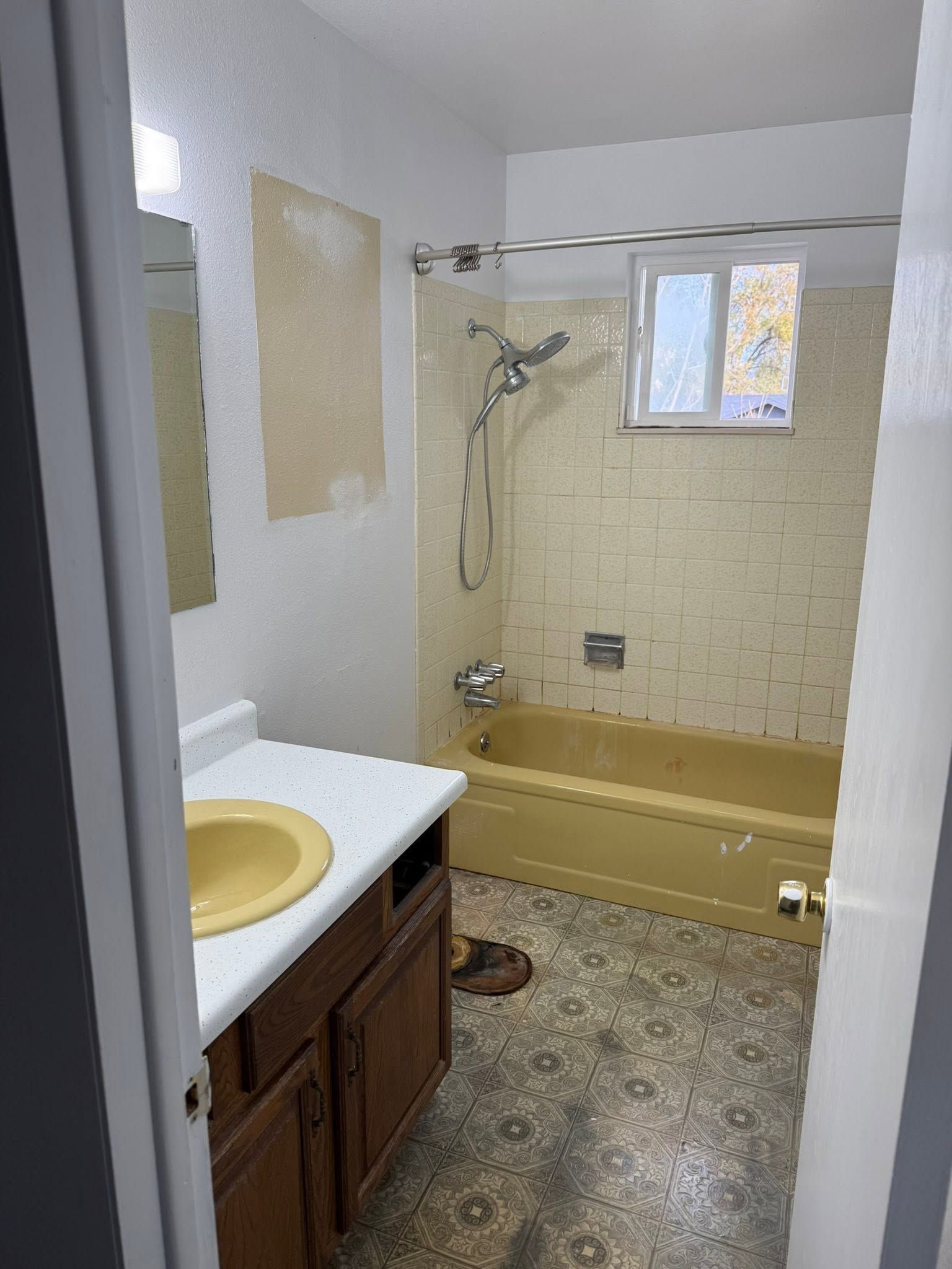 Small beige bathroom with sink vanity, bathtub-shower, and window light