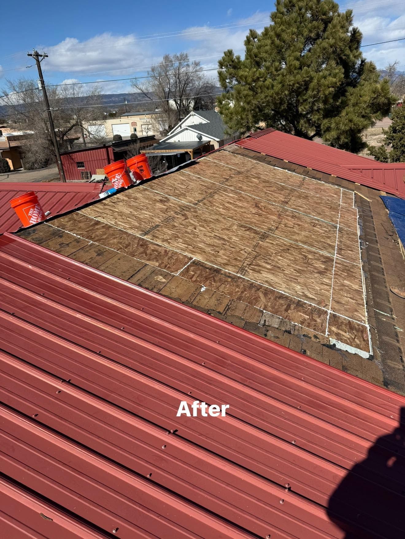 Roof repair after photo showing red metal roofing and exposed underlayment on a house ceiling.