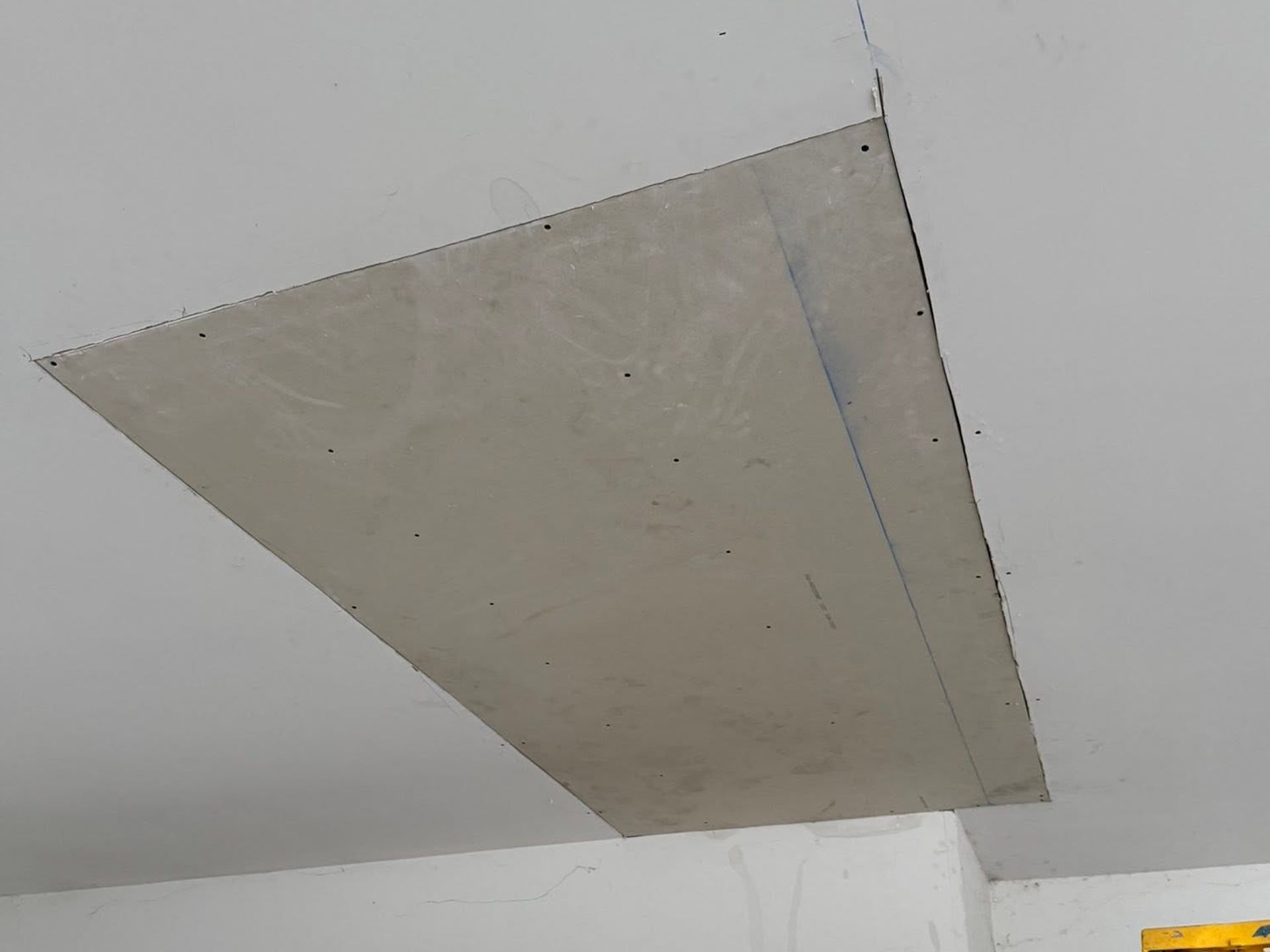Large gray panel patch on a white ceiling with visible seams and edges