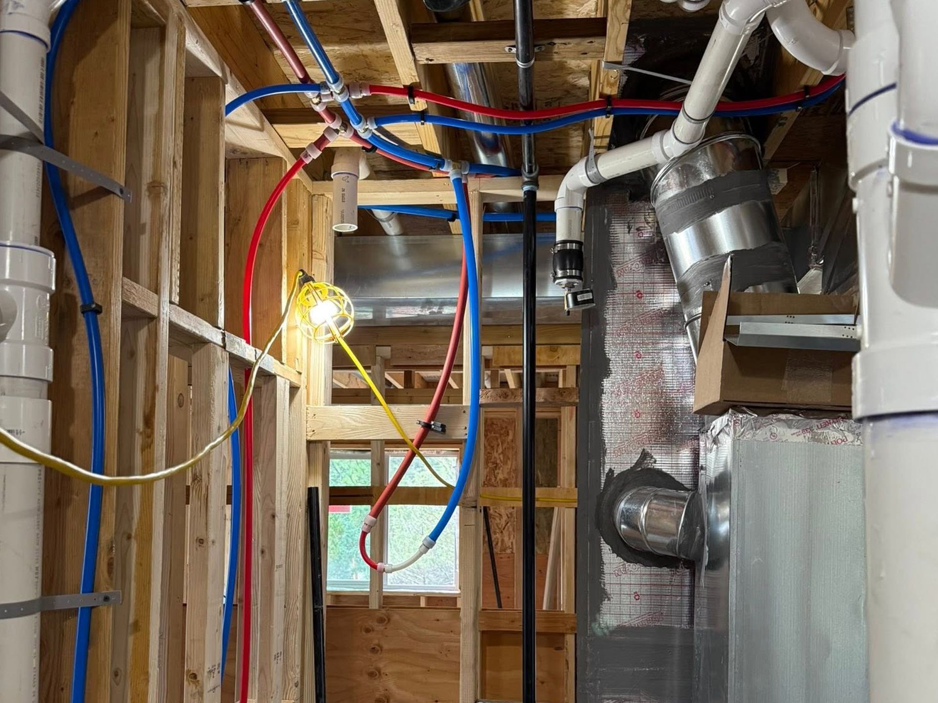 Partially finished basement with exposed framing, HVAC ducts, and hanging red and blue wires