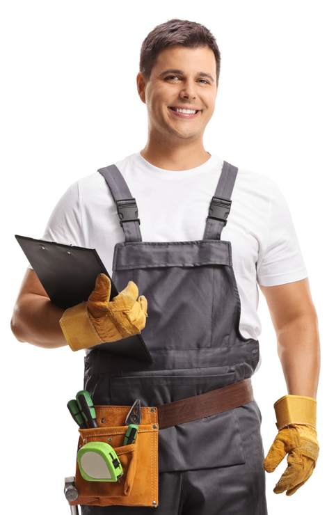 Smiling worker in gray overalls with tools and gloves, holding a clipboard against a white background
