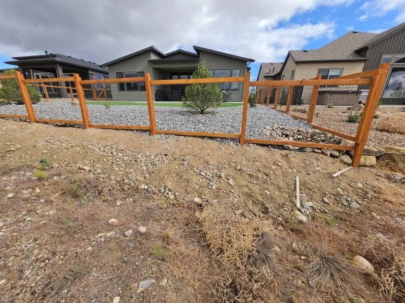 Orange fence around a gravel yard in front of modern houses under a partly cloudy sky