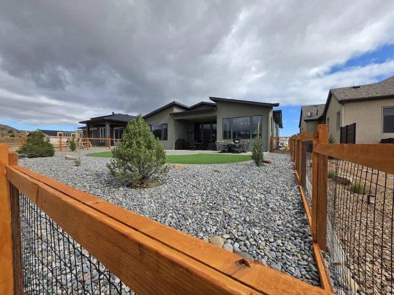 Modern house with gravel yard, orange fence, and cloudy sky