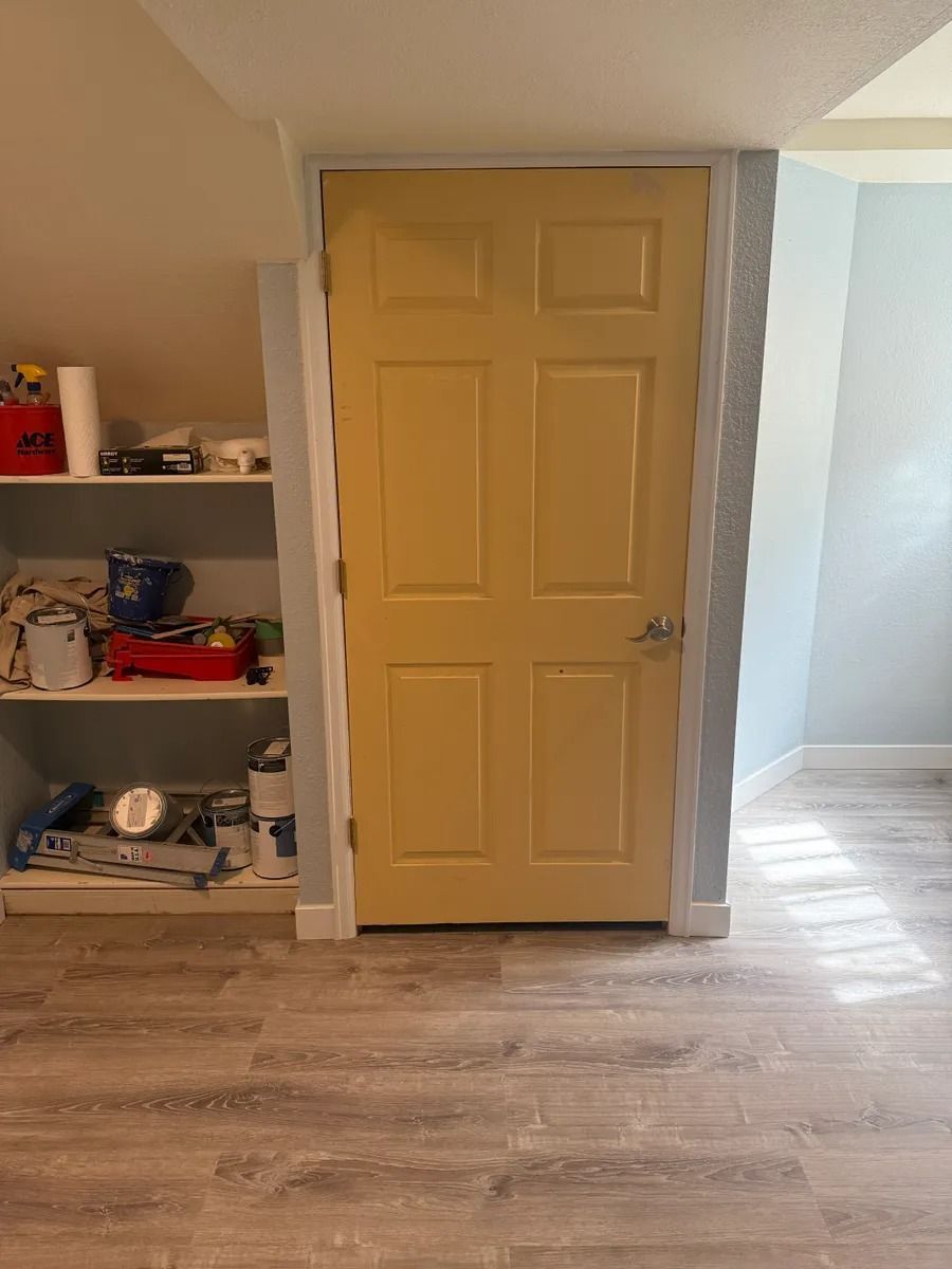 Yellow door beside built-in shelves in a small room with wood flooring