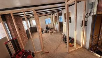 Unfinished basement with exposed wooden framing, concrete floor, and tools scattered around the space.