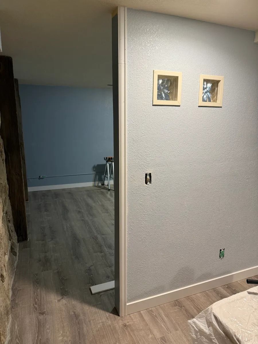 Hallway with light gray walls, dark wood floor, and two framed pictures on the wall