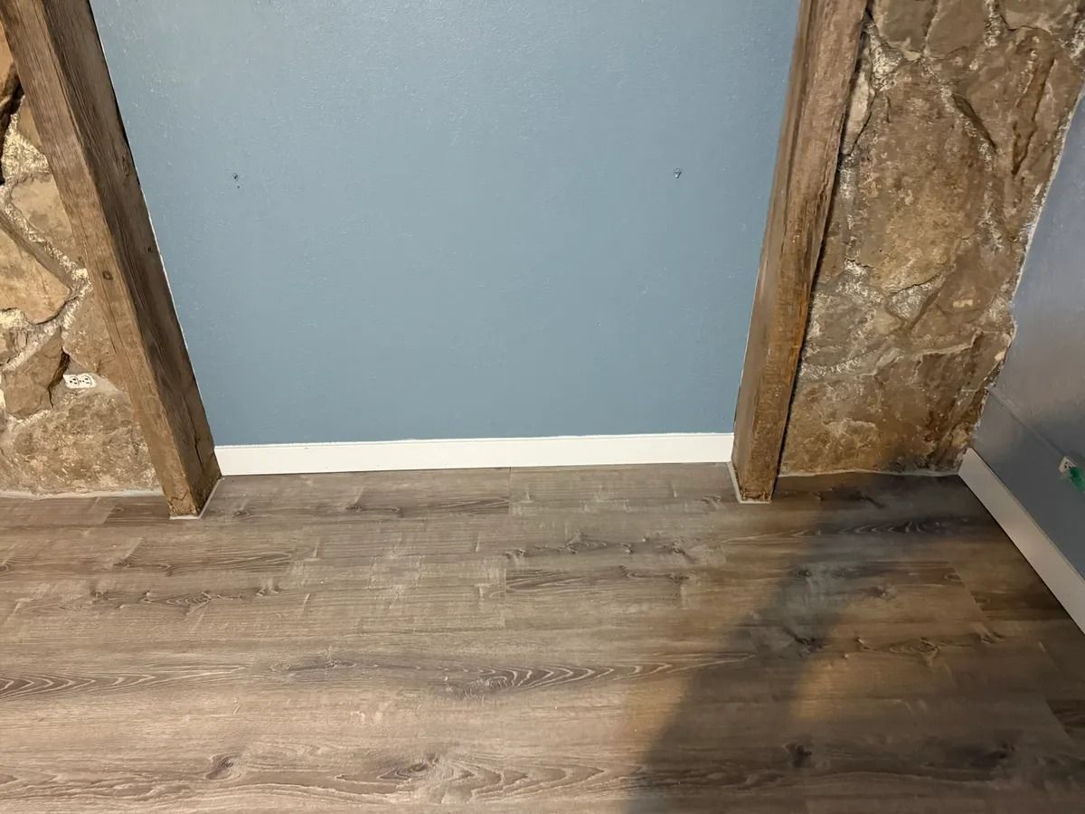 Doorway with blue wall, exposed wood trim, and gray wood-look flooring.