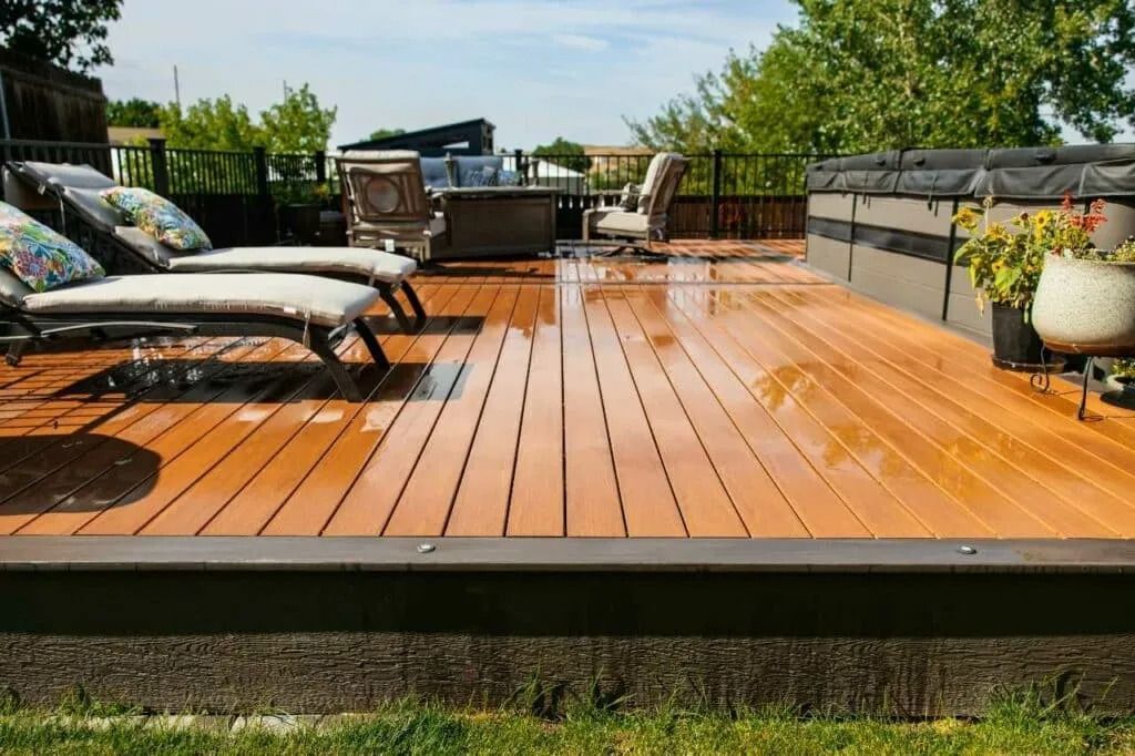 Wooden backyard deck with lounge chairs, outdoor seating, and a wet sheen after rain