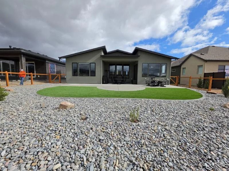 Single-story house with a gravel front yard and green lawn under a cloudy sky.