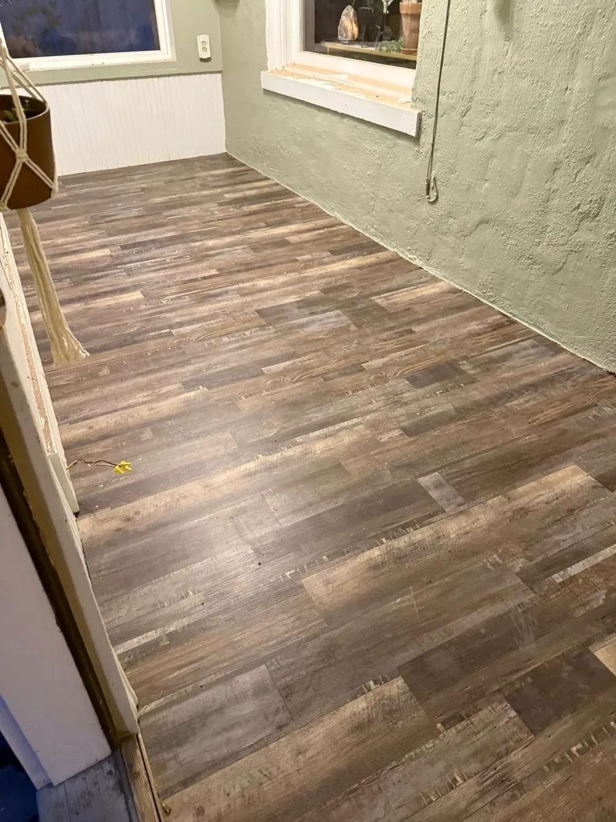 Empty hallway with wood-look flooring and green textured walls, viewed through a doorway.