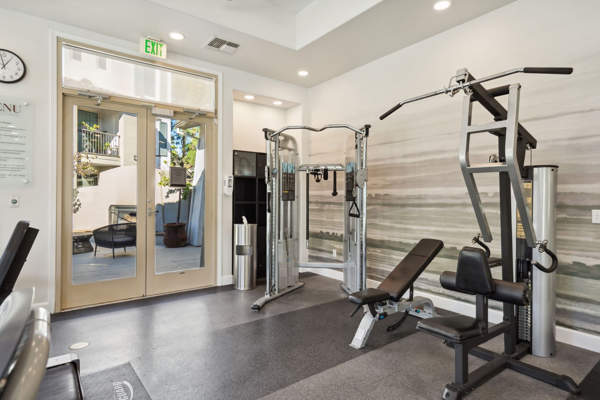 Interior of a residential gym with weight machines and a glass exit door.