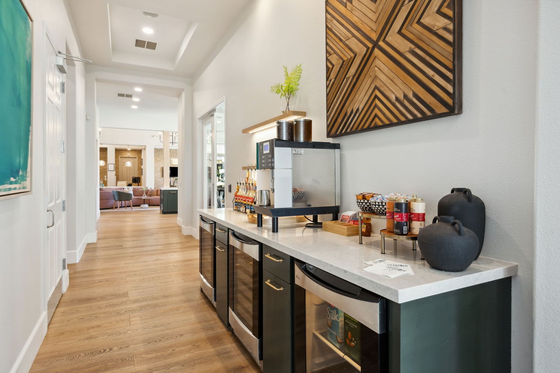 Bright hallway with a coffee station, espresso machine, and snack bar along a counter.