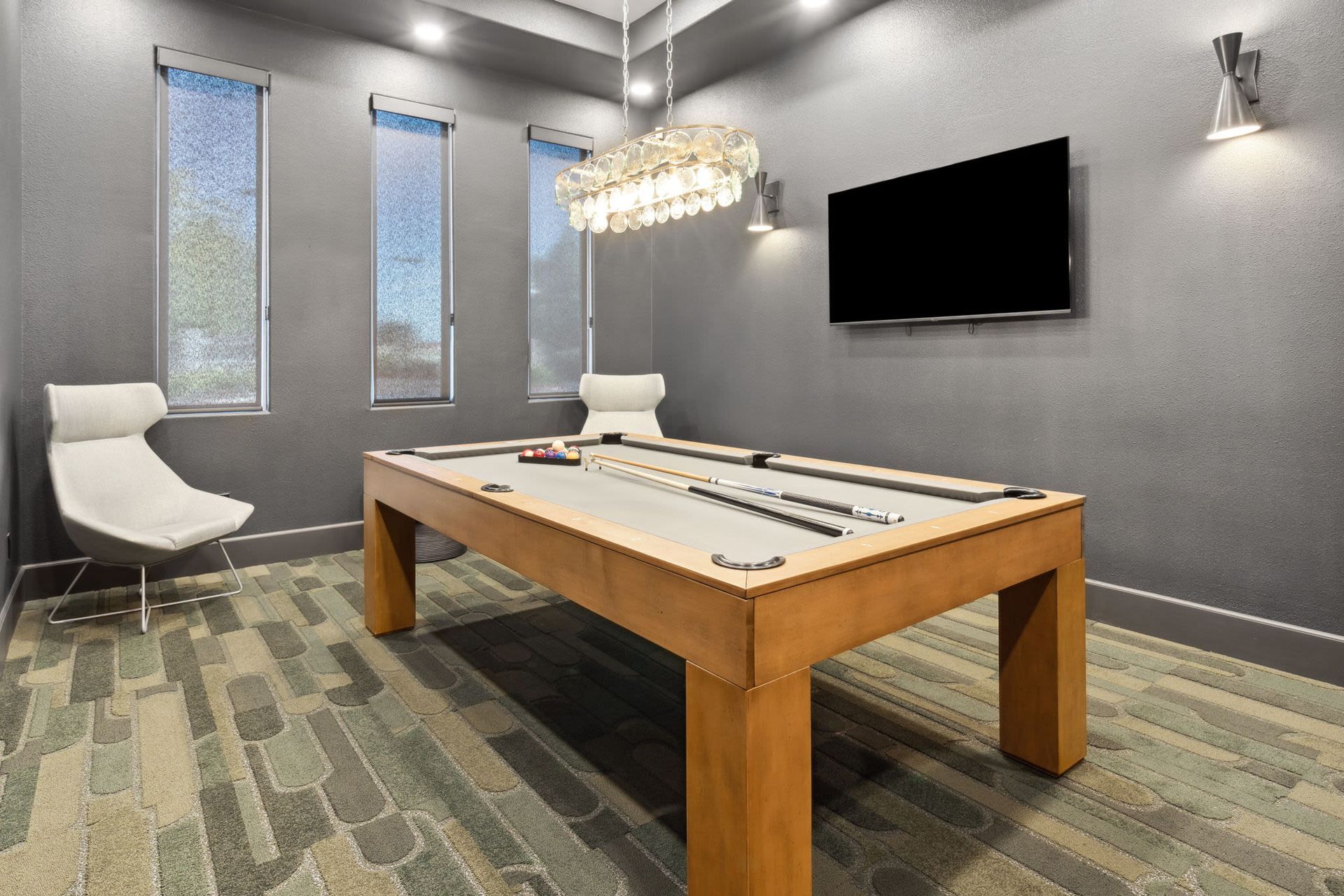 Indoor recreation room with a pool table, chandelier, seating, and a wall-mounted TV.