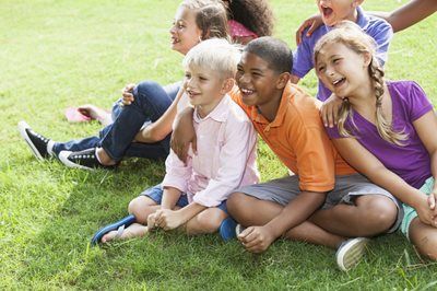 Children sitting together on grass, smiling and posing outdoors