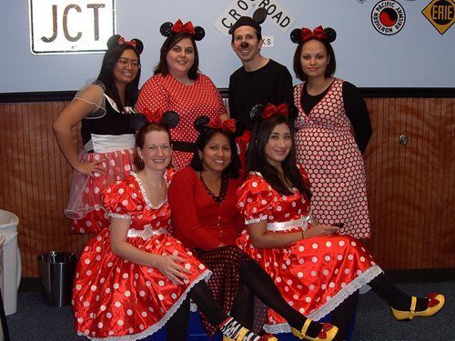 Six people in red polka-dot costumes posing indoors at a social event
