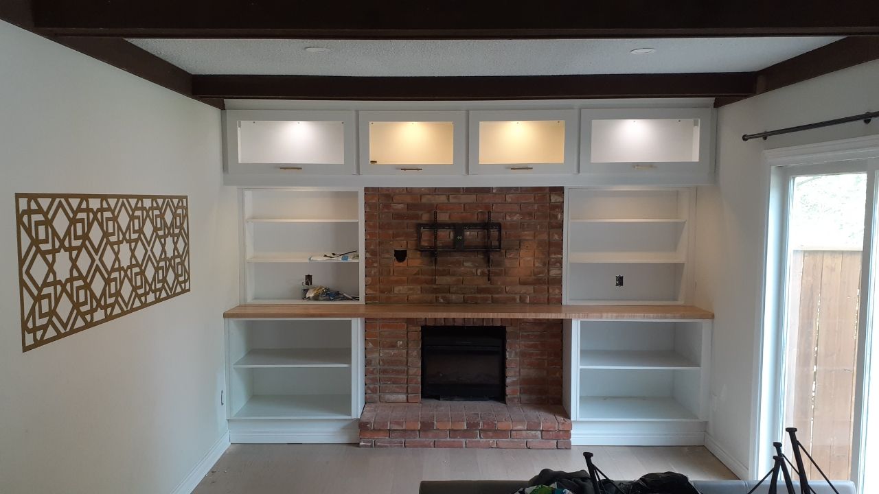 Living room with brick fireplace, built-in shelves, wood mantel, and decorative wall art