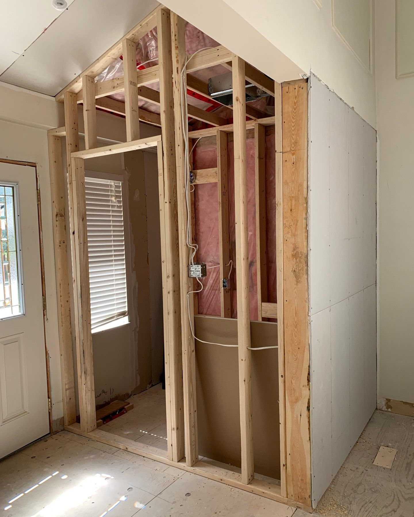 Framed wall under construction beside a doorway in a partially finished room.
