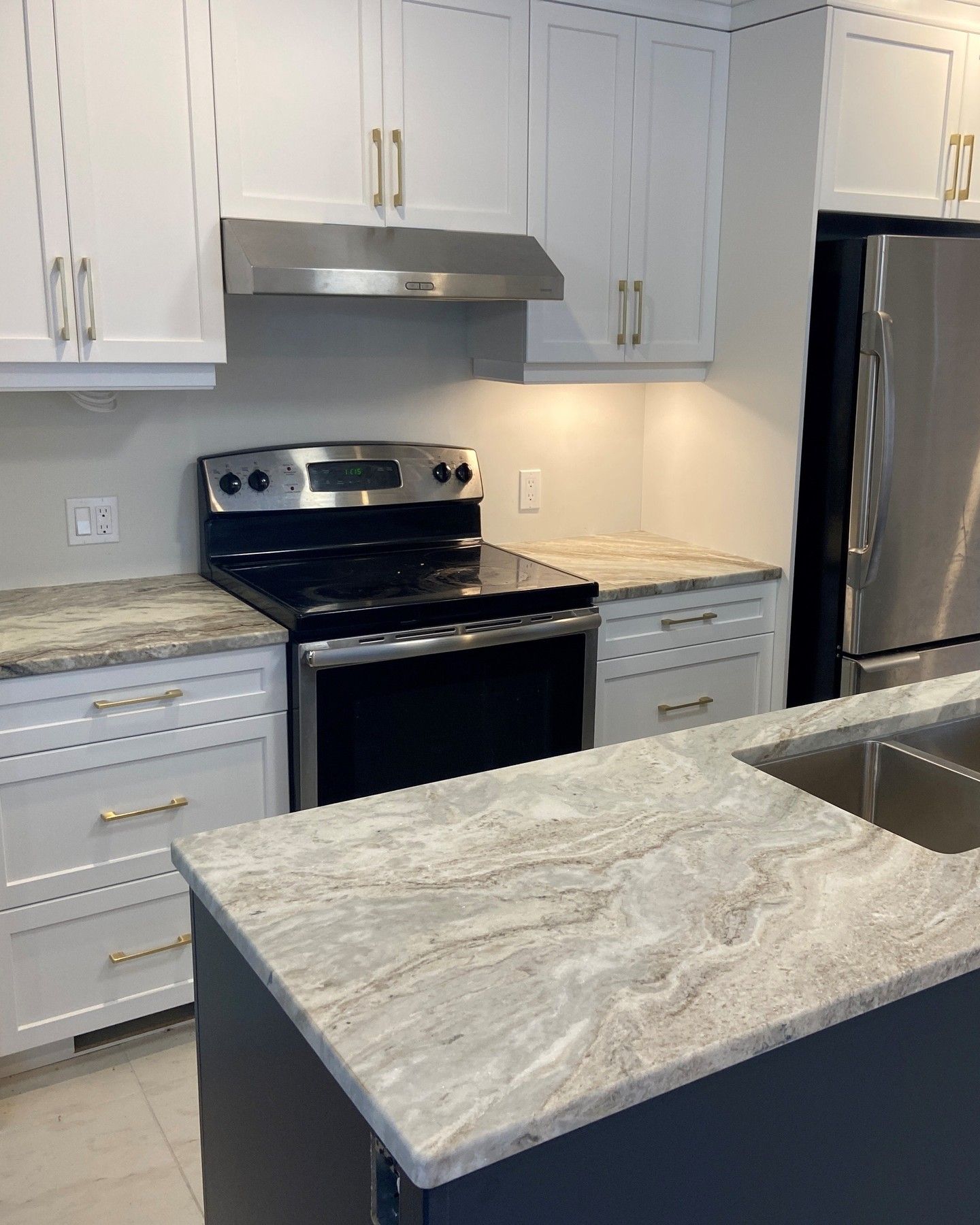 Modern kitchen with white cabinets, stainless steel stove and fridge, and a gray marble island countertop