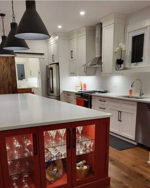Bright white kitchen with a red island, pendant lights, and hardwood floors