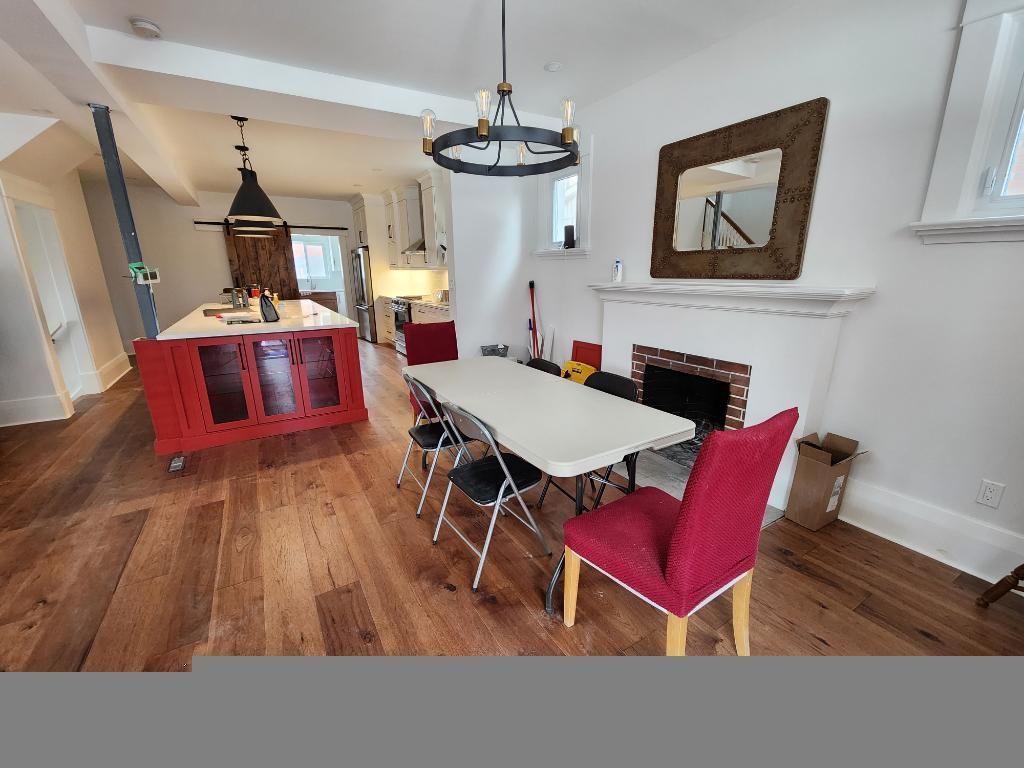 Modern kitchen and dining area with red chairs, white table, and wood floors