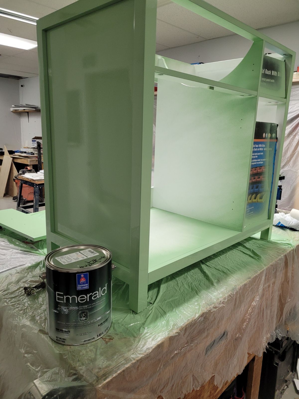 A can of emerald paint is sitting on a table next to a green cabinet.