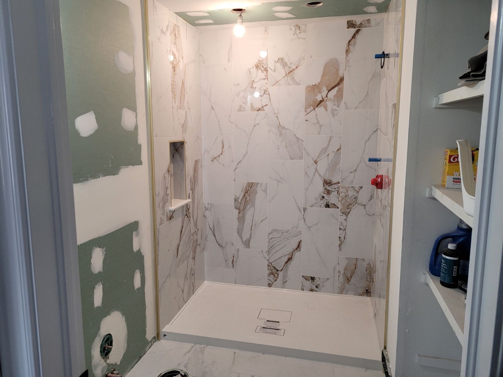 A bathroom under construction with marble tiles and a walk in shower.
