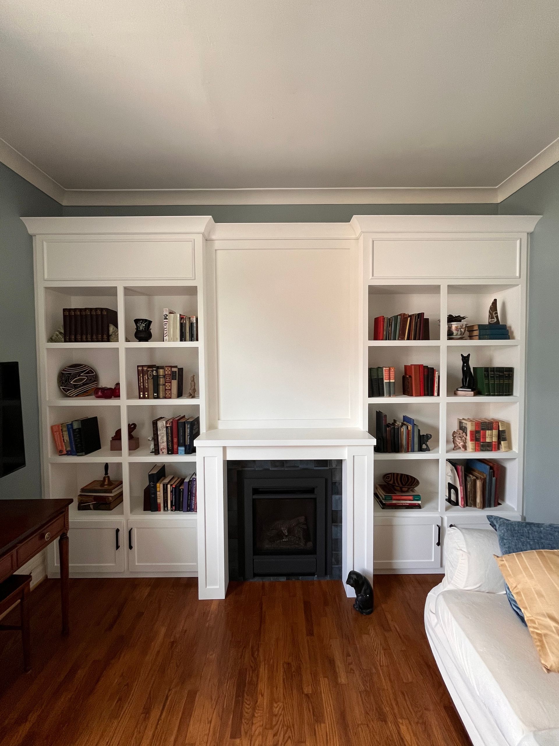 Living room with white built-in bookshelves flanking a fireplace and hardwood floors