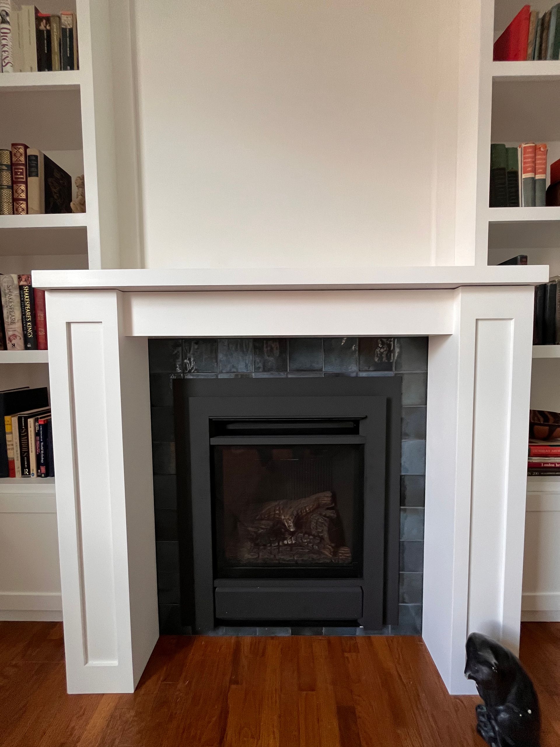 White fireplace mantel centered between built-in bookshelves in a cozy living room