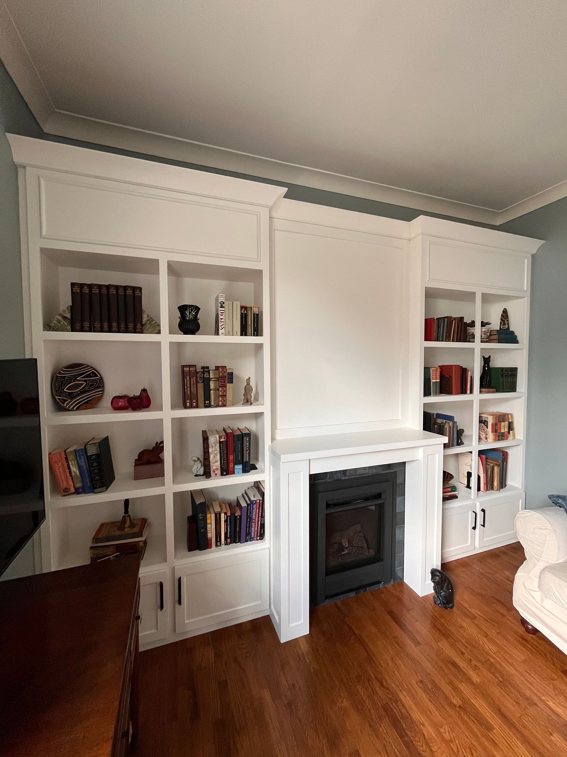 White built-in bookshelves flanking a fireplace in a hardwood-floored living room
