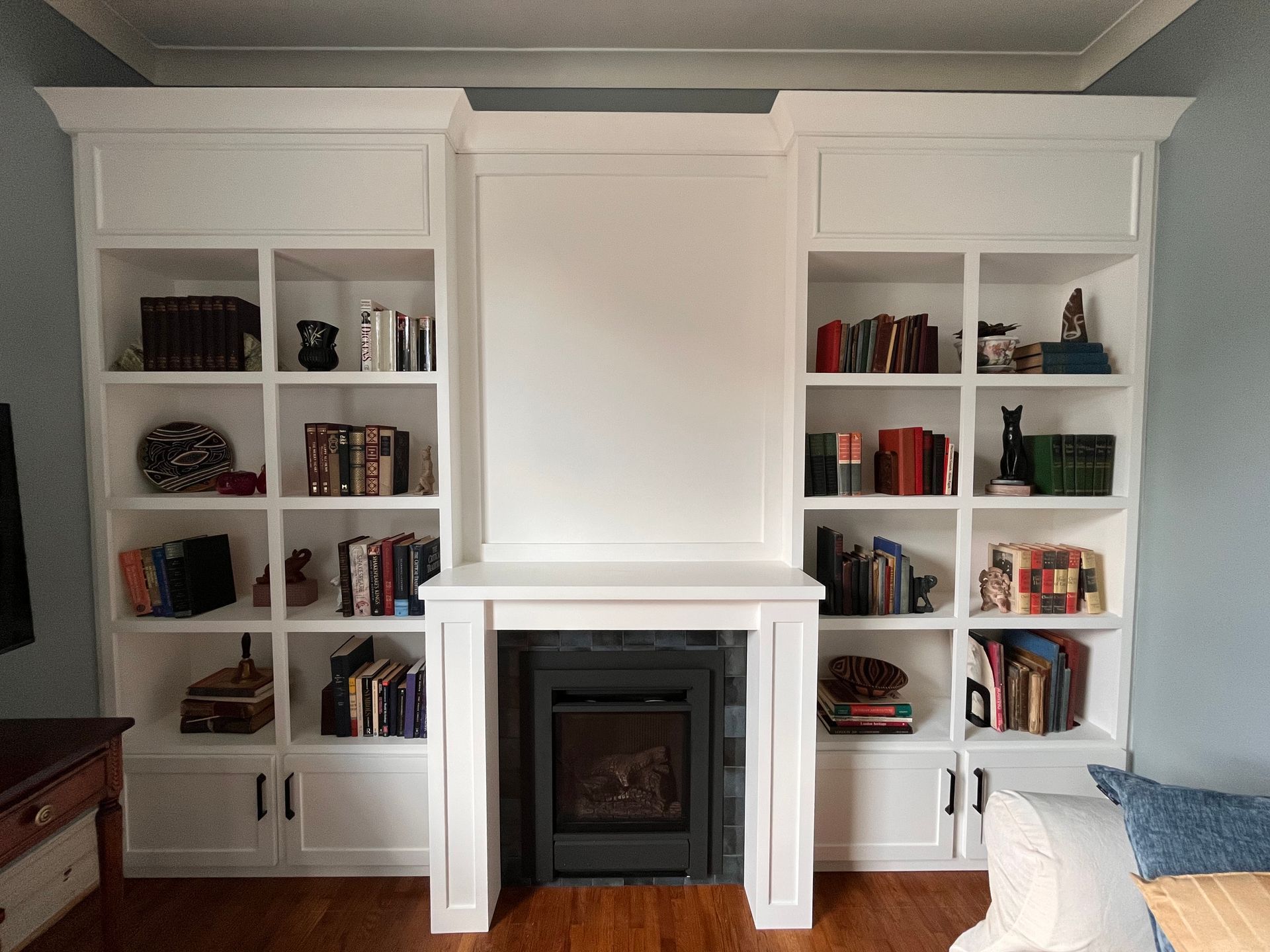 Built-in white bookshelves flanking a fireplace in a bright living room