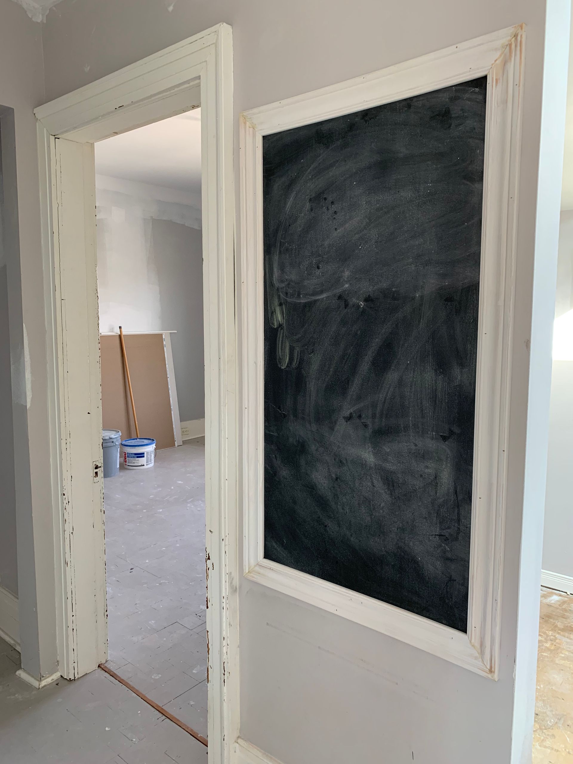 Hallway with an unfinished framed opening and a dark chalkboard-style panel in a white wall