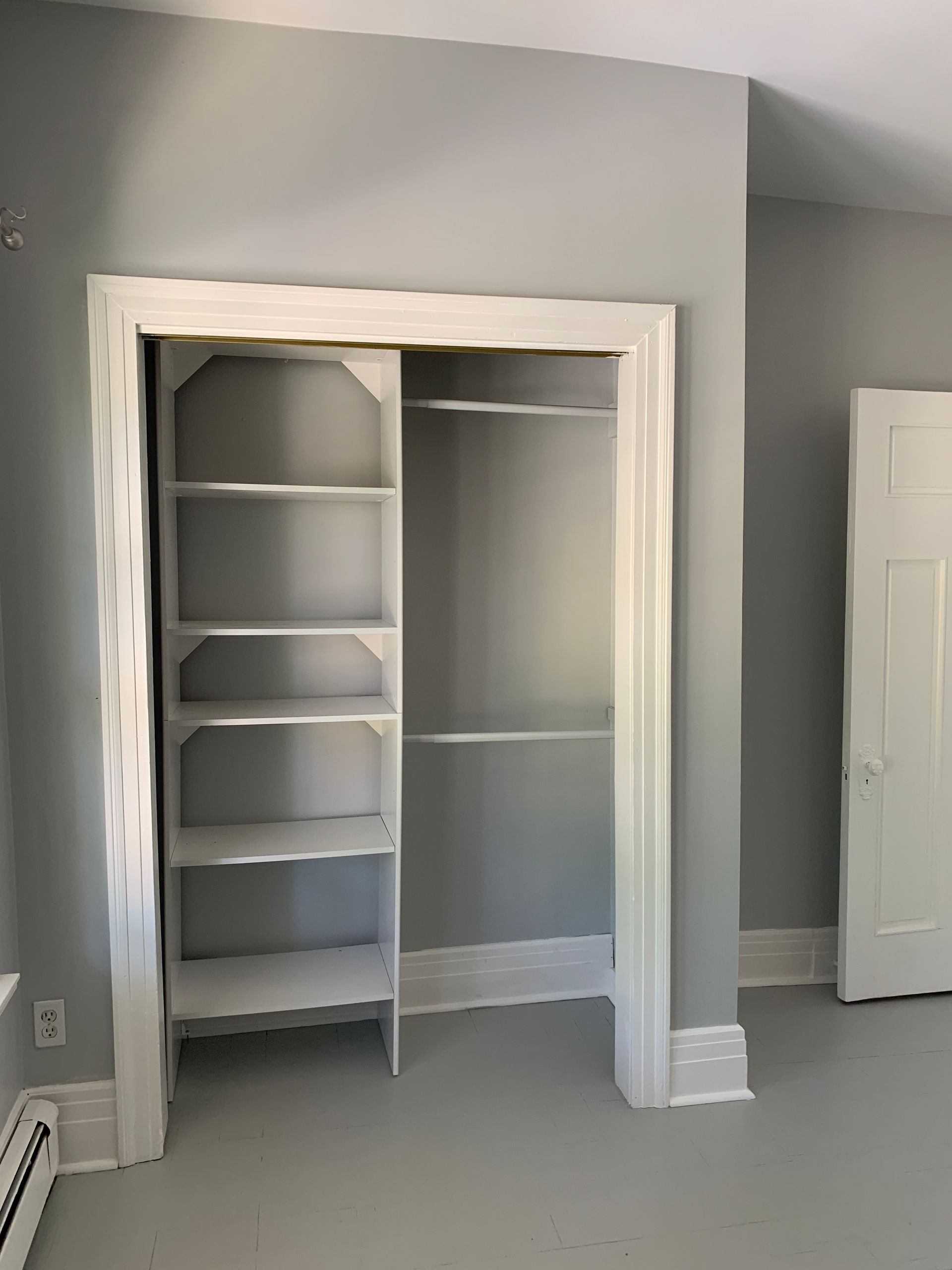 Empty built-in closet with shelves and hanging rods in a light gray room