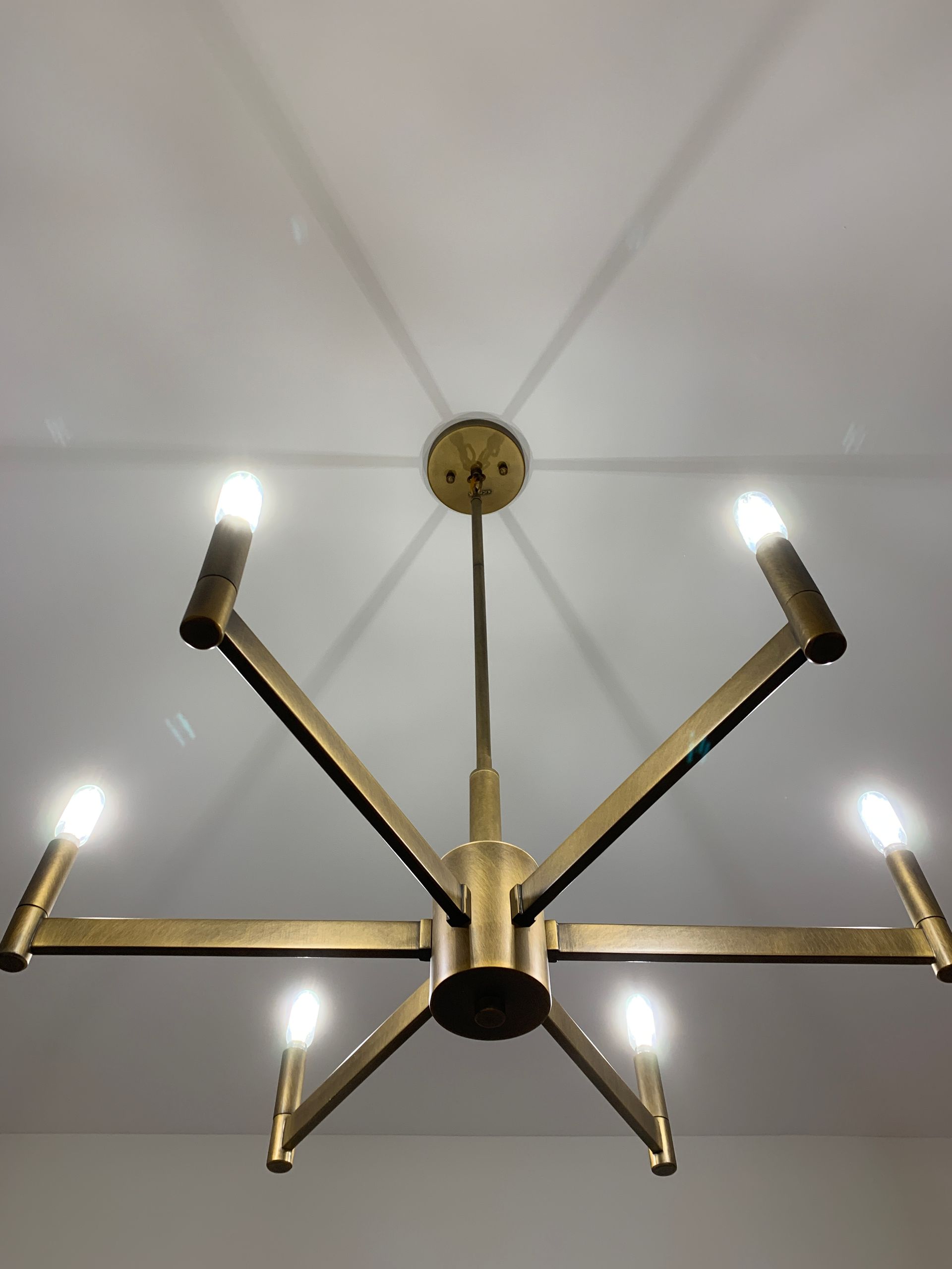 A brass chandelier is hanging from a white ceiling