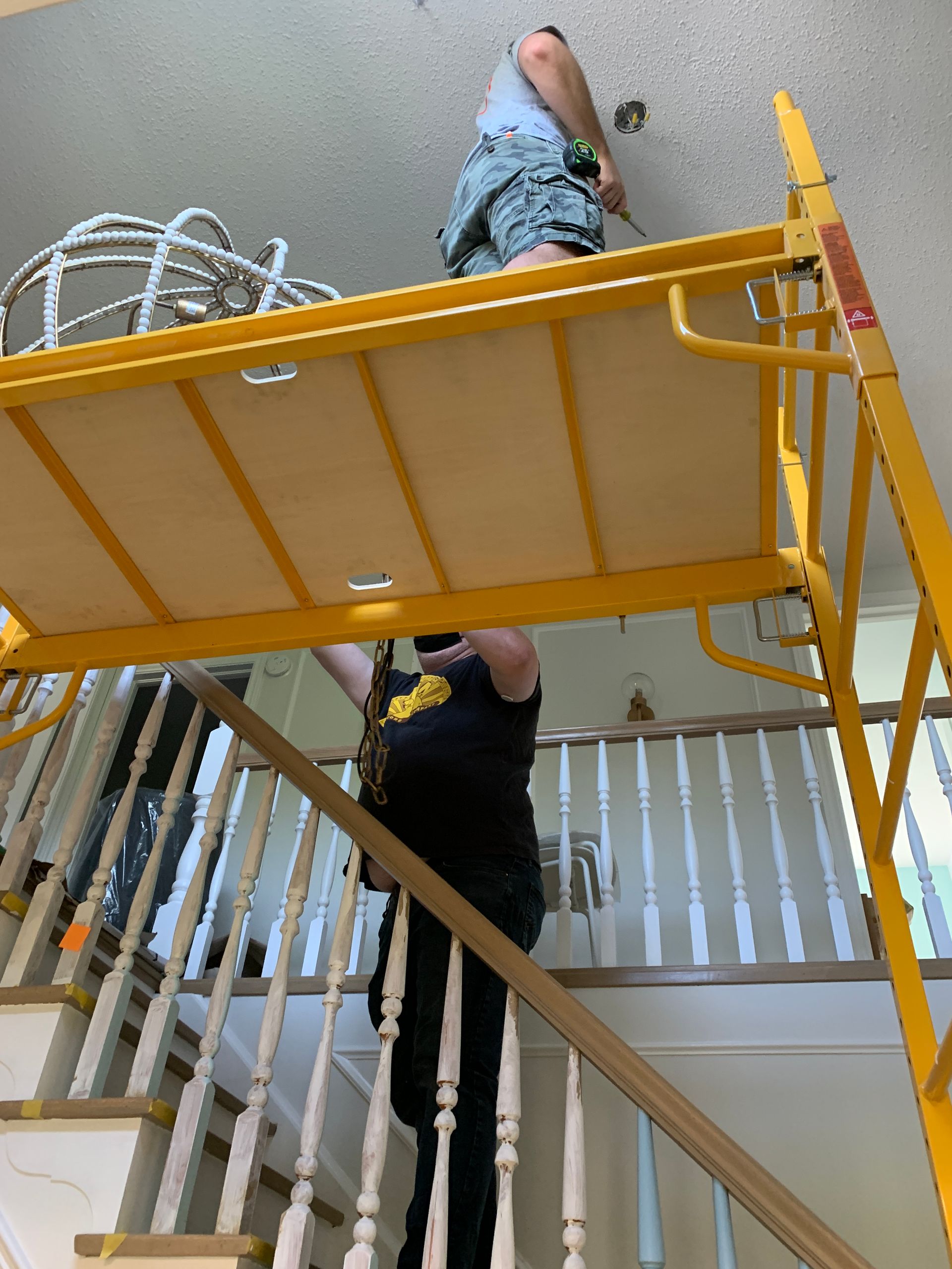 A man is standing on a yellow scaffolding over a set of stairs