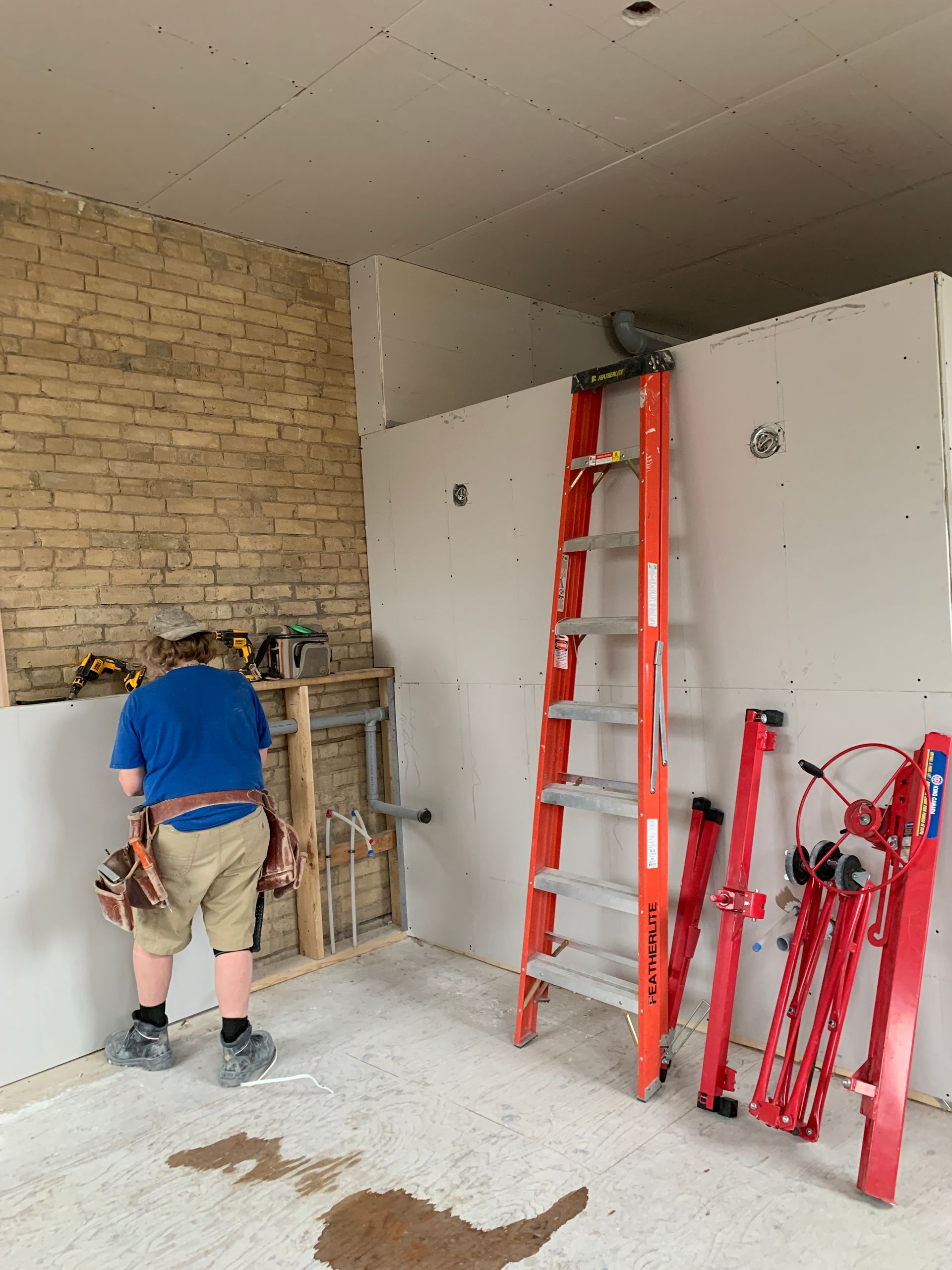 A man is standing in a room next to a ladder.