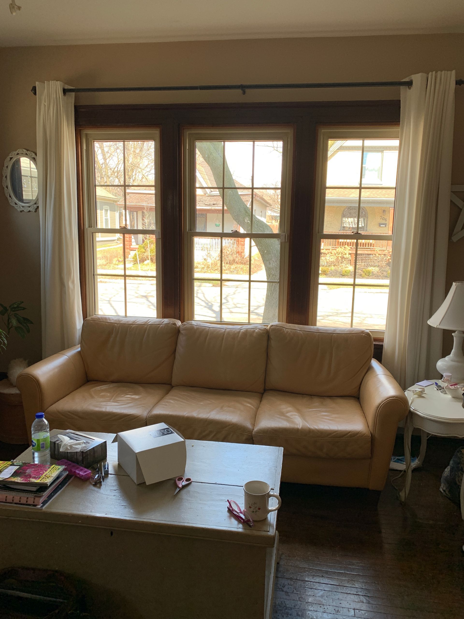 Living room with a beige sofa, coffee table, and large window with curtains and blinds
