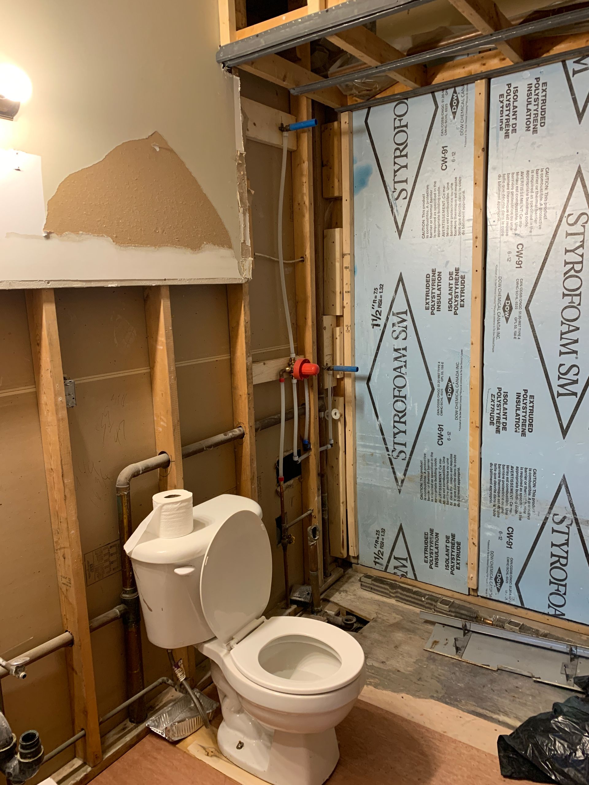 A toilet is sitting in a bathroom under construction.