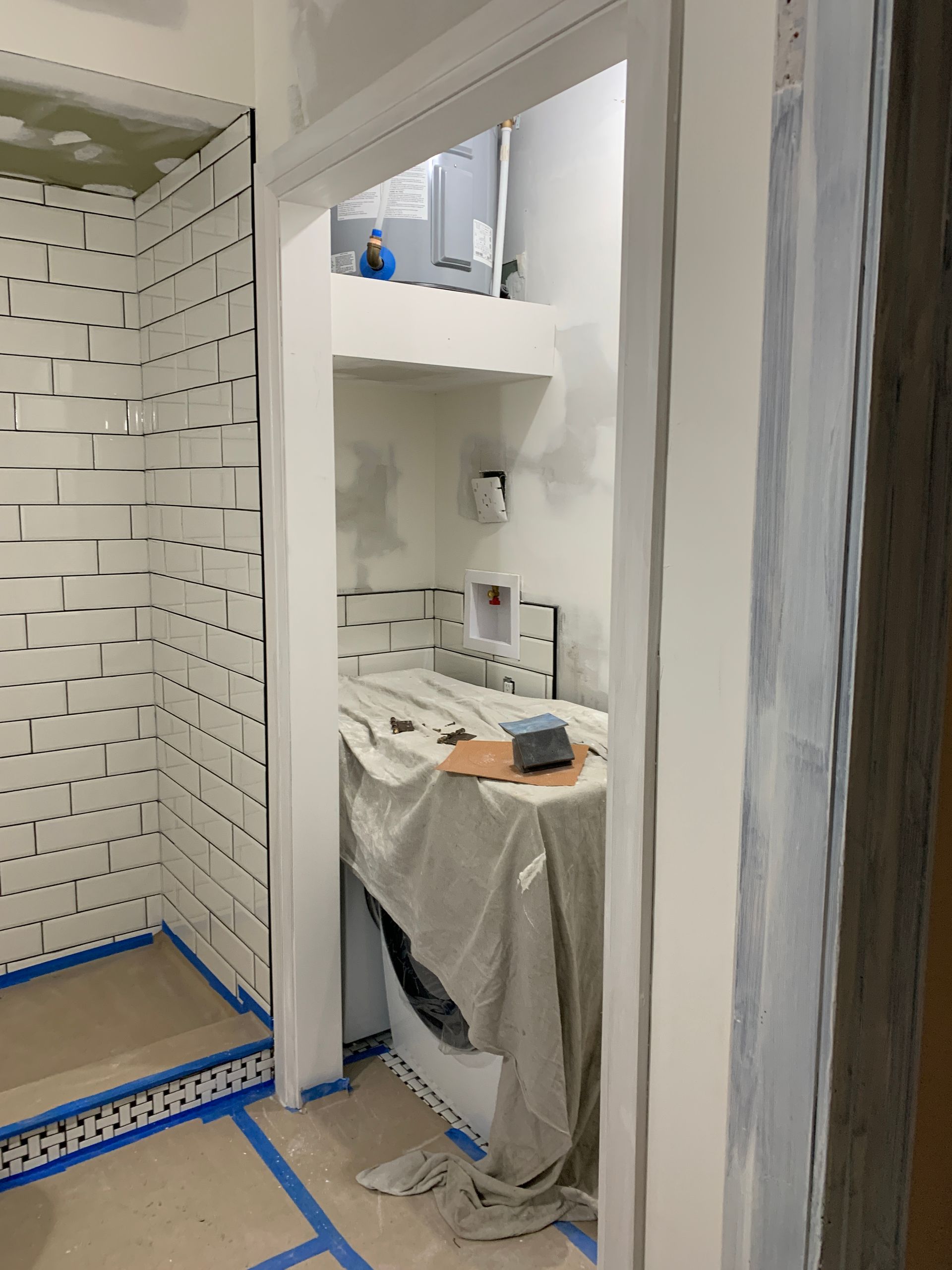 A bathroom with white tiles and a washer and dryer.