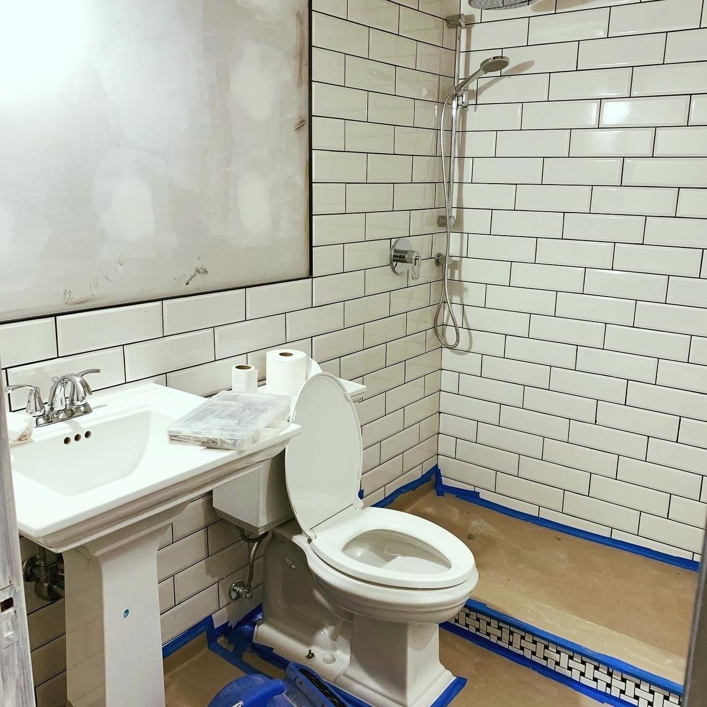 Small tiled bathroom with a sink, mirror, and toilet beside a walk-in shower area.