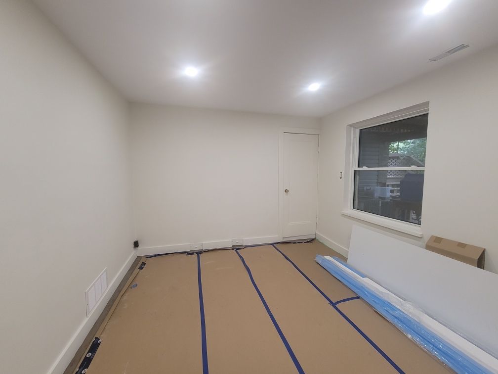 An empty room with a window and a blue tape on the floor.